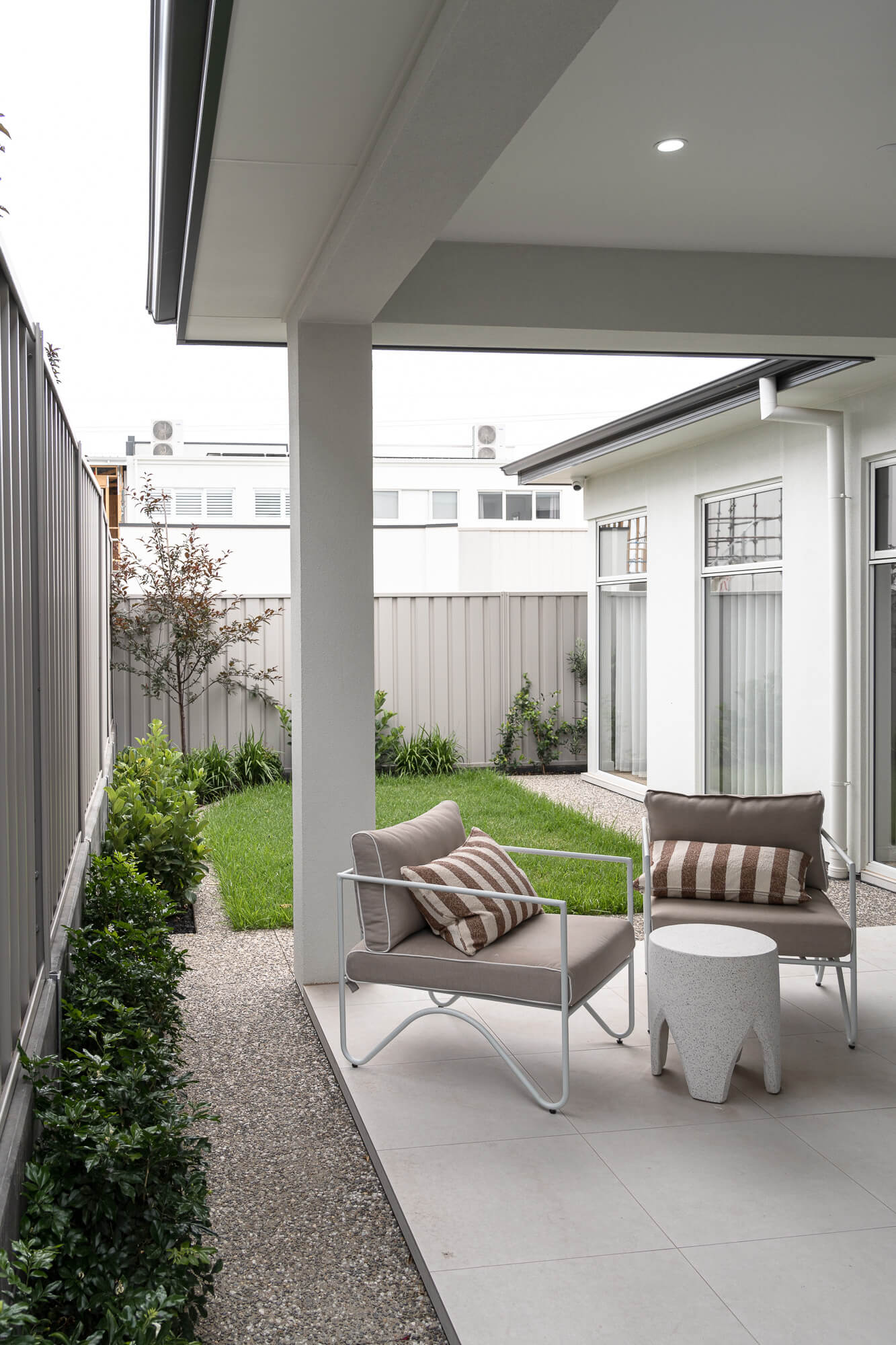 A modern residential garden in Melbourne featuring structured planting, lawn, and outdoor seating area.